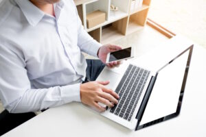 man-holding-credit-card-hand-entering-security-code-using-smart-phone-laptop-keyboard-online-shopping-concept - Computer Center W dzisiejszych czasach, gdy praca zdalna i mobilność stały się kluczowymi aspektami naszego życia zawodowego, coraz więcej osób poszukuje niezawodnych i wydajnych laptopów